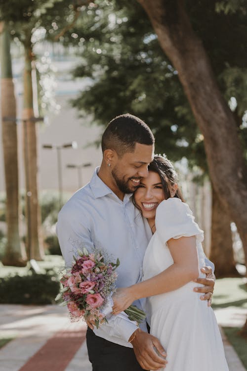 Elegant Couple Hugging on a Sidewalk and Smiling 