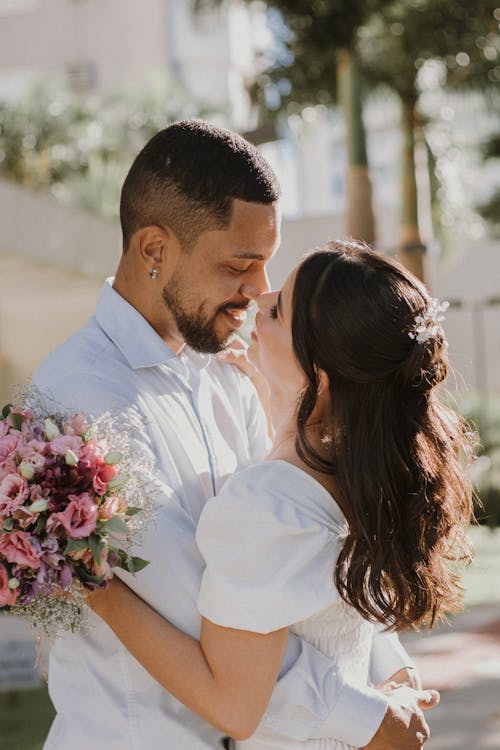 A Couple Hugging on a Sidewalk and Smiling 