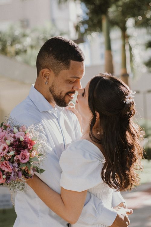 Free A romantic couple sharing a tender moment outdoors, holding a vibrant bouquet of flowers. Stock Photo