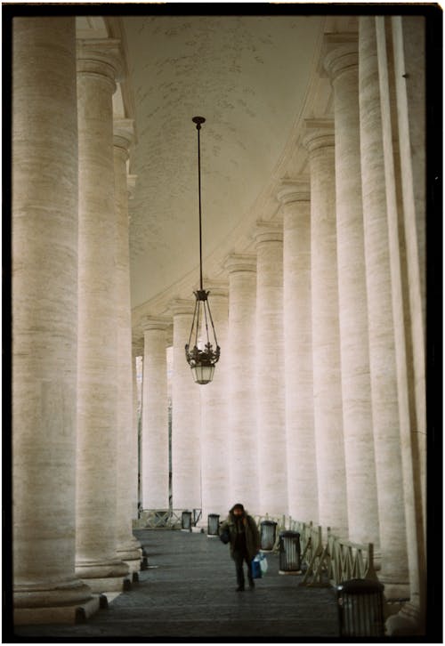 A person walking down a hallway with pillars