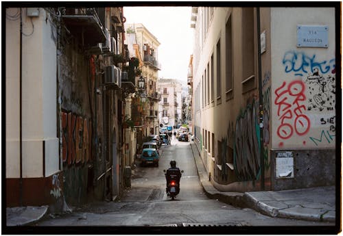 A man riding a motorcycle down a narrow alley