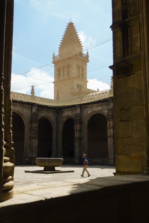 A man walking through an archway in a courtyard