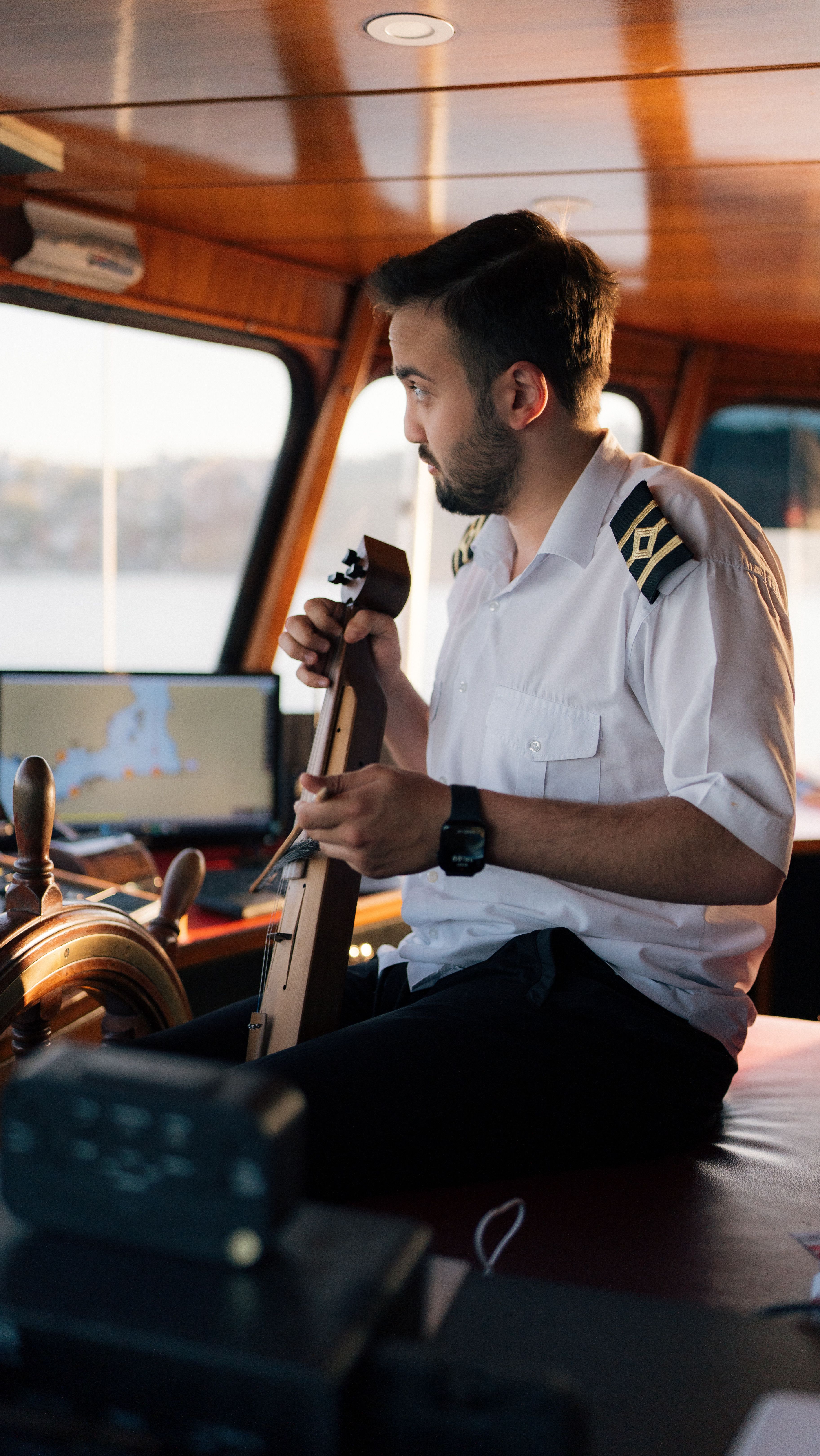 A ship captain playing a string instrument in the cabin, showcasing a musical moment on a ferry.