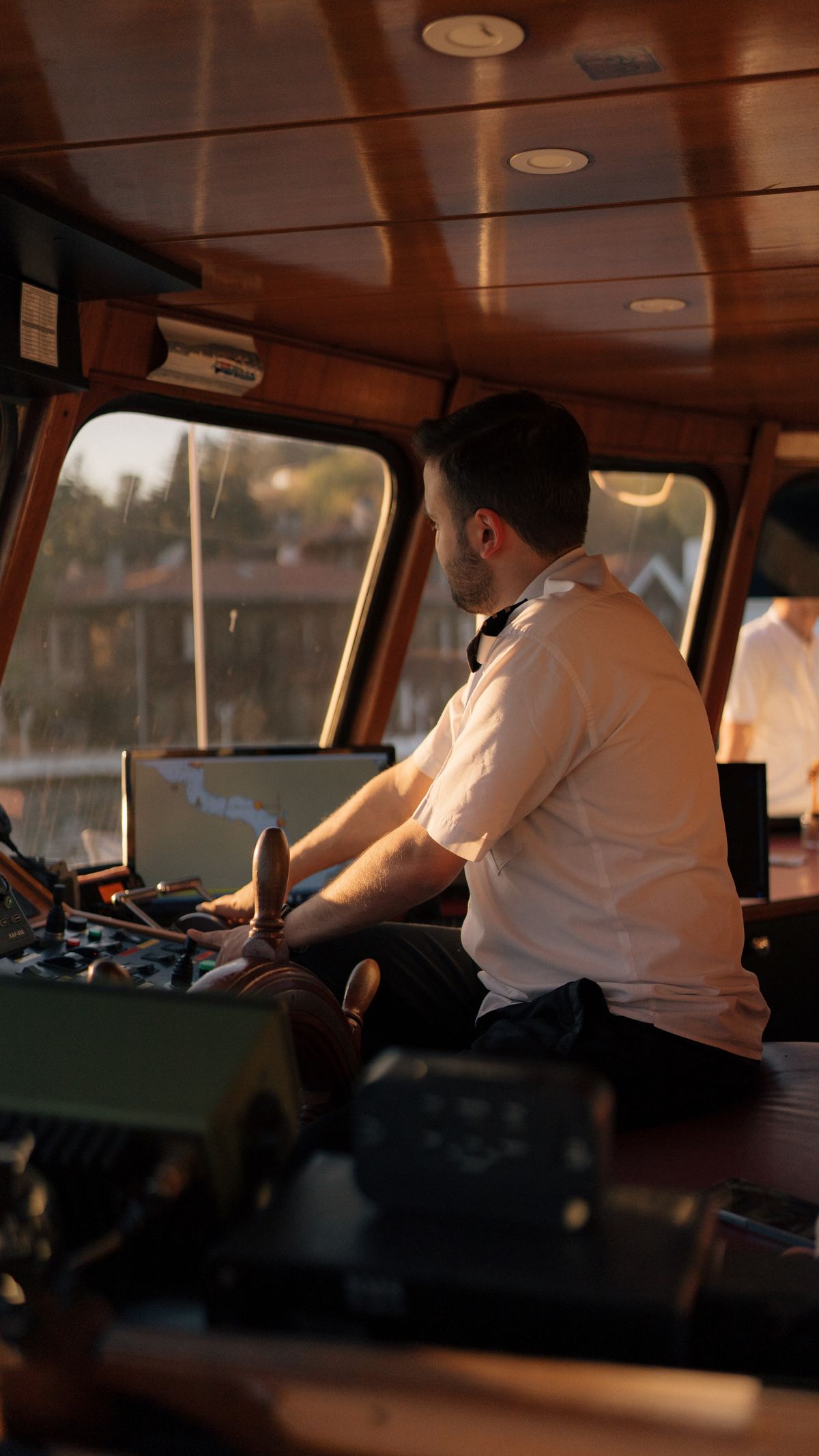 Captain at the helm inside the yacht wheelhouse during golden hour