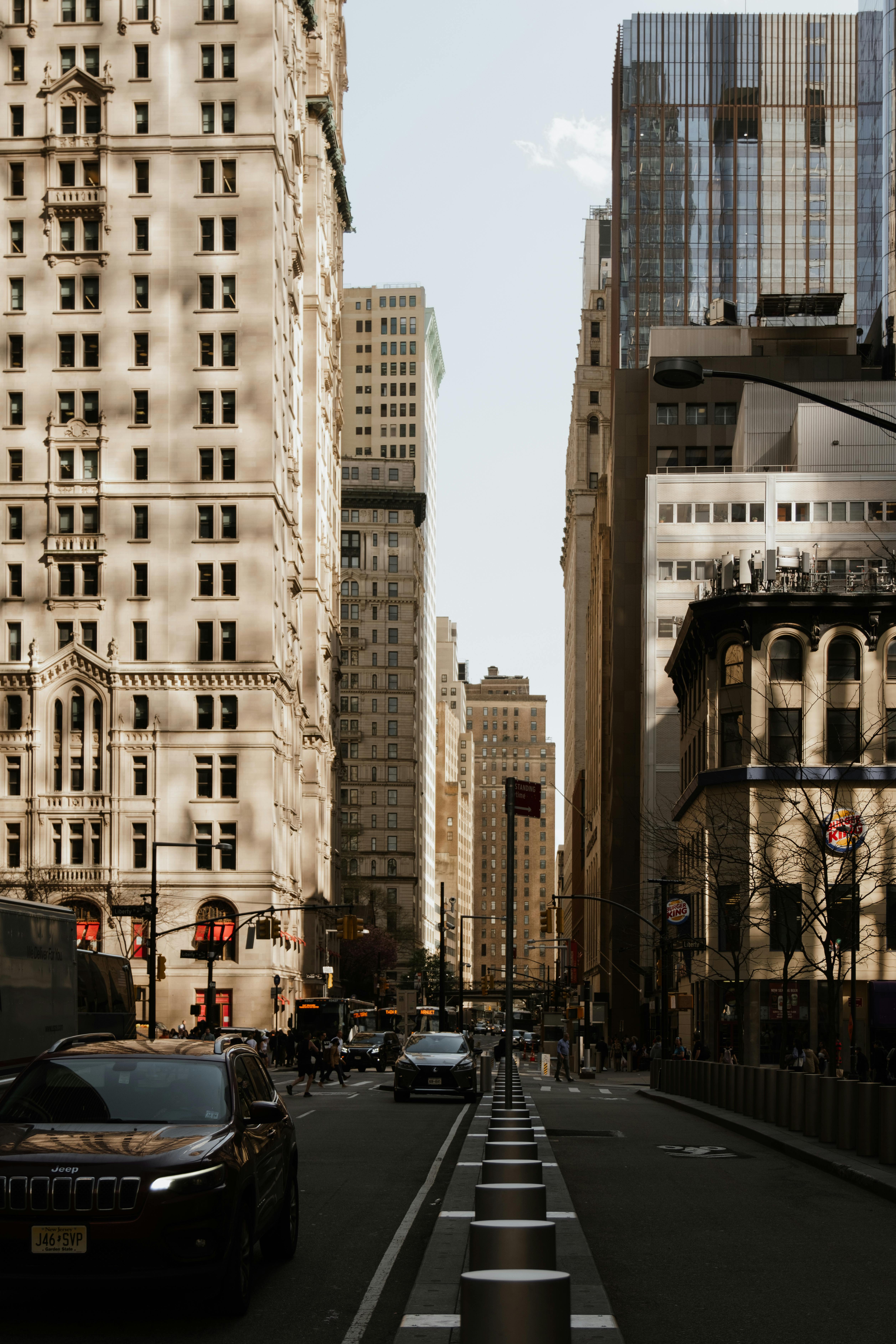 City street view with towering skyscrapers and busy traffic under a clear sky.