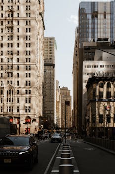 City street view with towering skyscrapers and busy traffic under a clear sky.