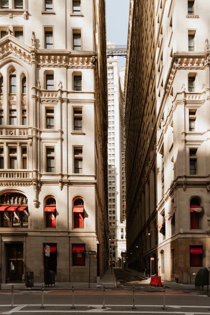 View of a narrow urban alley between historic buildings with sunlight casting shadows, capturing modern city vibes.