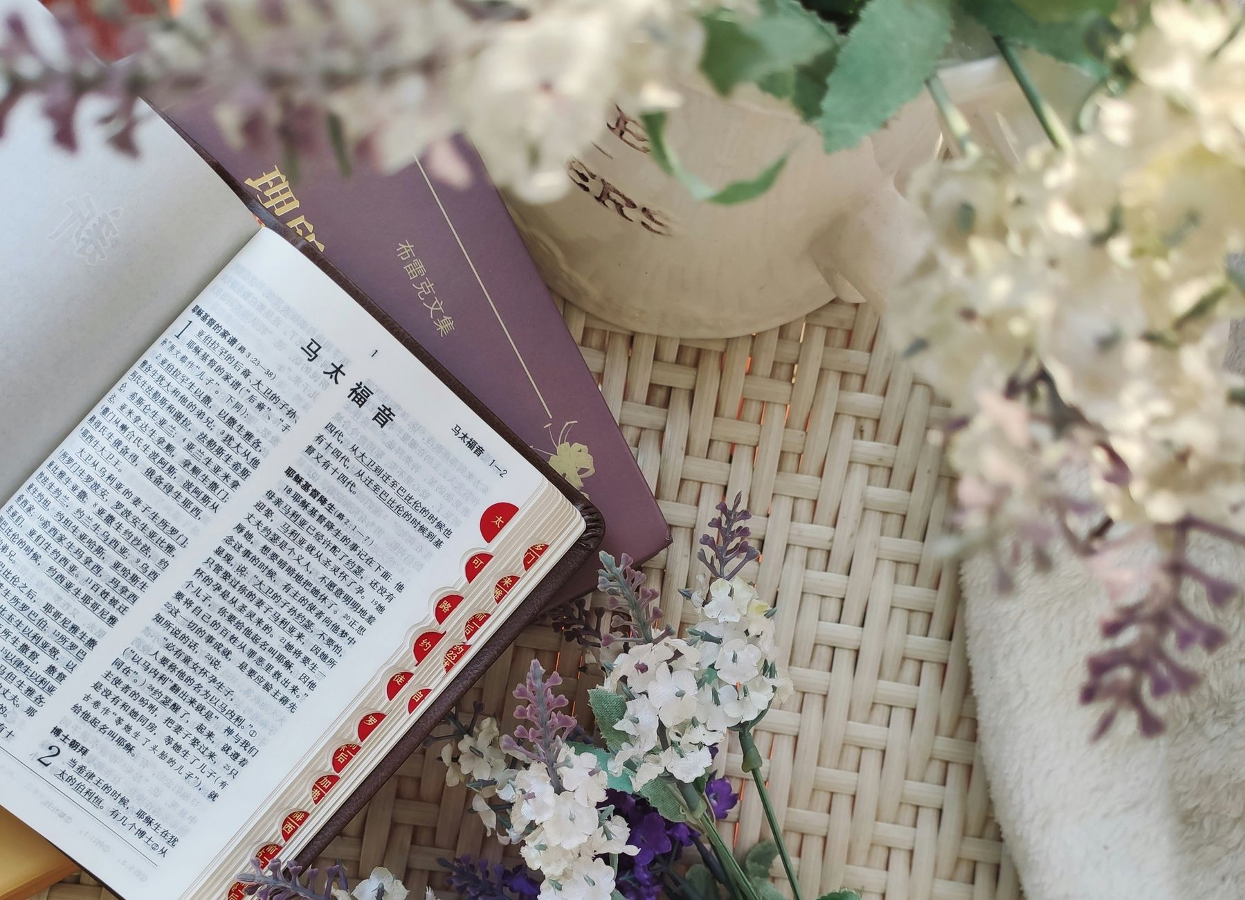 An open Chinese Bible on a woven surface with floral decorations, exuding a serene atmosphere.