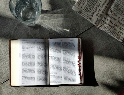 A book open on a table with a glass of water