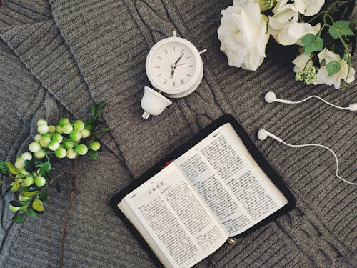 A book, flowers and a clock on a table