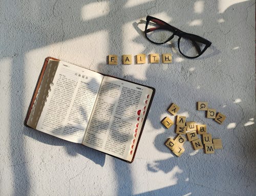 A book and glasses on a table with the word faith