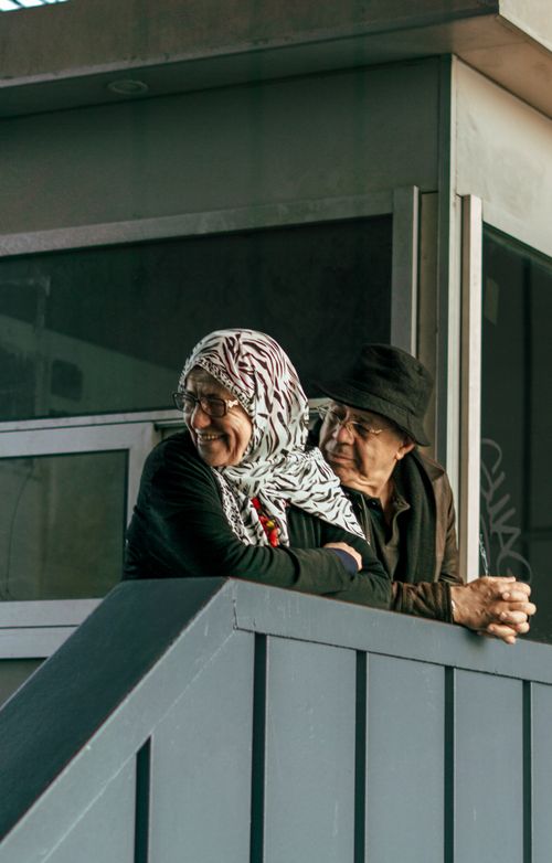 Free Charming elderly couple smiles together on a porch, enjoying the sunlight. Stock Photo