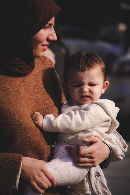 Free A mother holding her baby outdoors in sunlight, expressing love and care. Stock Photo