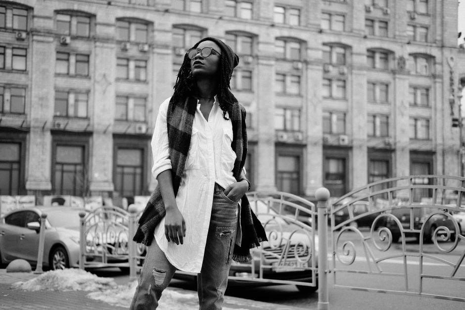 Confident woman in a scarf and beanie posing on an urban street.