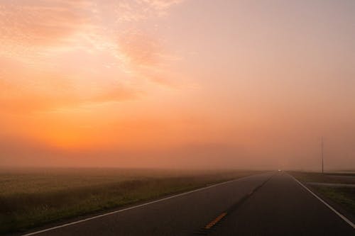 A road with a foggy sky and a car driving