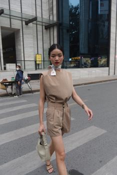 Elegant woman in fashionable attire walking across an urban crosswalk.