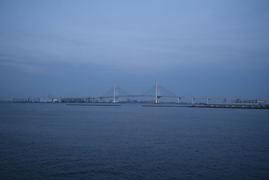 Serene view of Yokohama Bay Bridge during twilight, showcasing calm sea and architectural beauty.