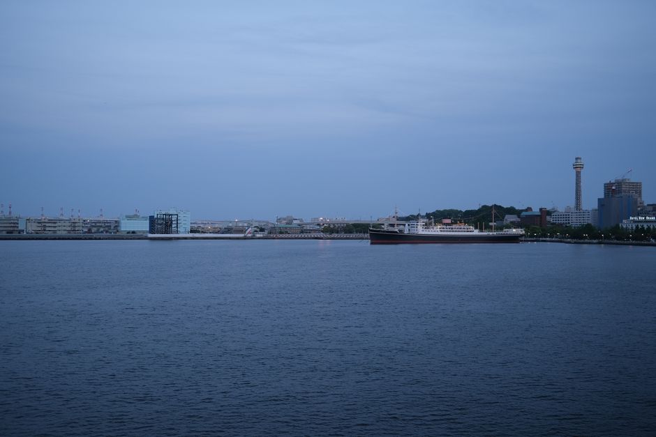 Beautiful cityscape of Yokohama harbor at dusk, featuring buildings and a cargo ship.