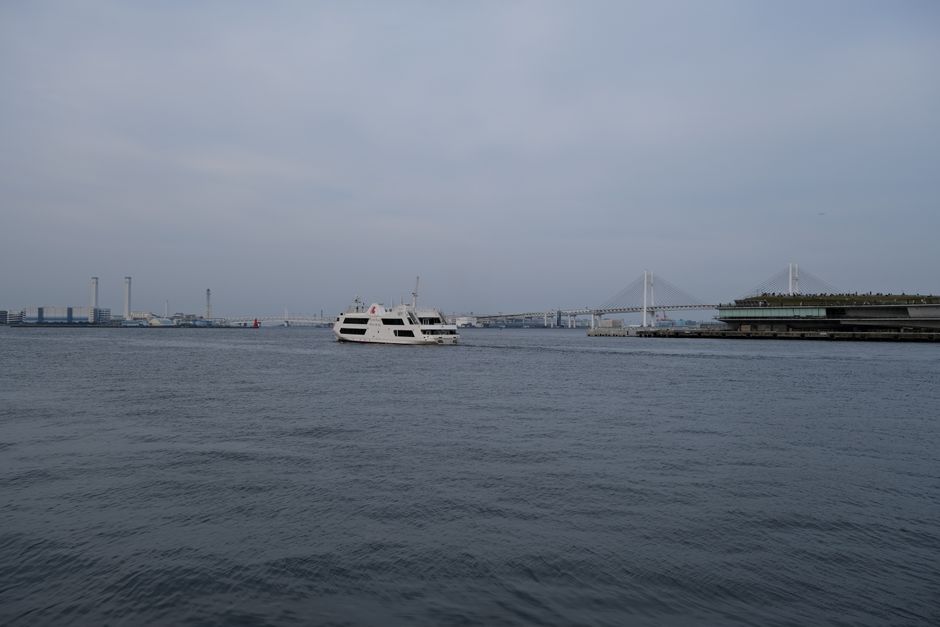 A serene view of a cruise ship in Yokohama Bay with the iconic bridge in the background.