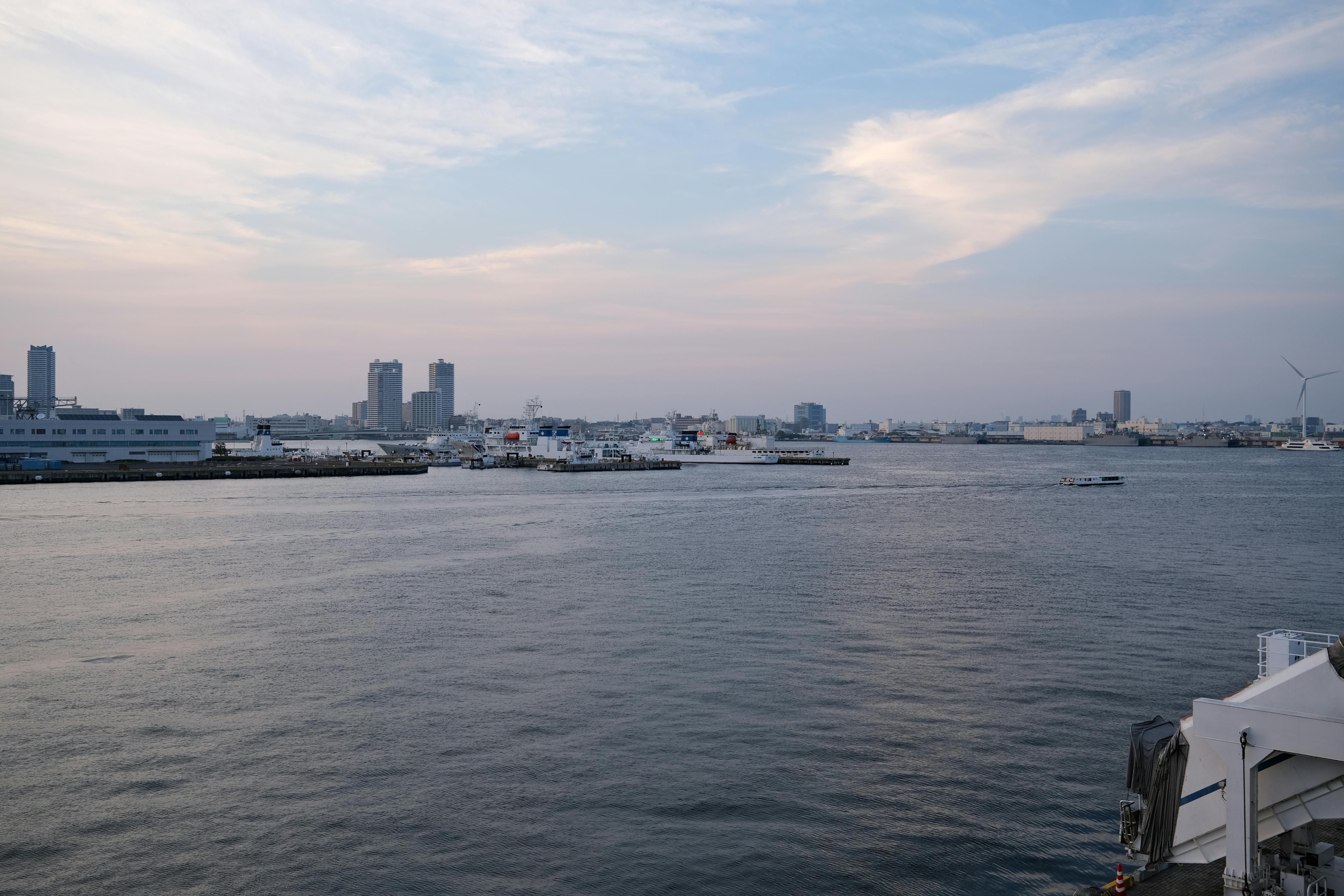 Tranquil view of Yokohama harbor during twilight, showcasing city skyline and calm waters.