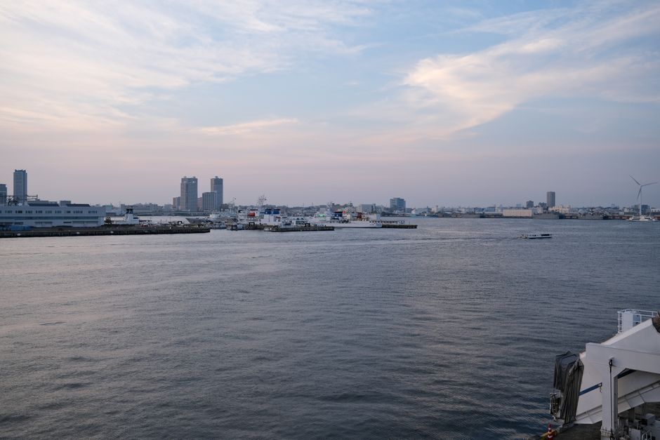 Tranquil view of Yokohama harbor during twilight, showcasing city skyline and calm waters.