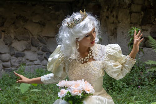 A woman dressed in a wedding gown and holding a bouquet of flowers