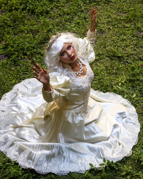 A woman in a white dress is sitting on the grass