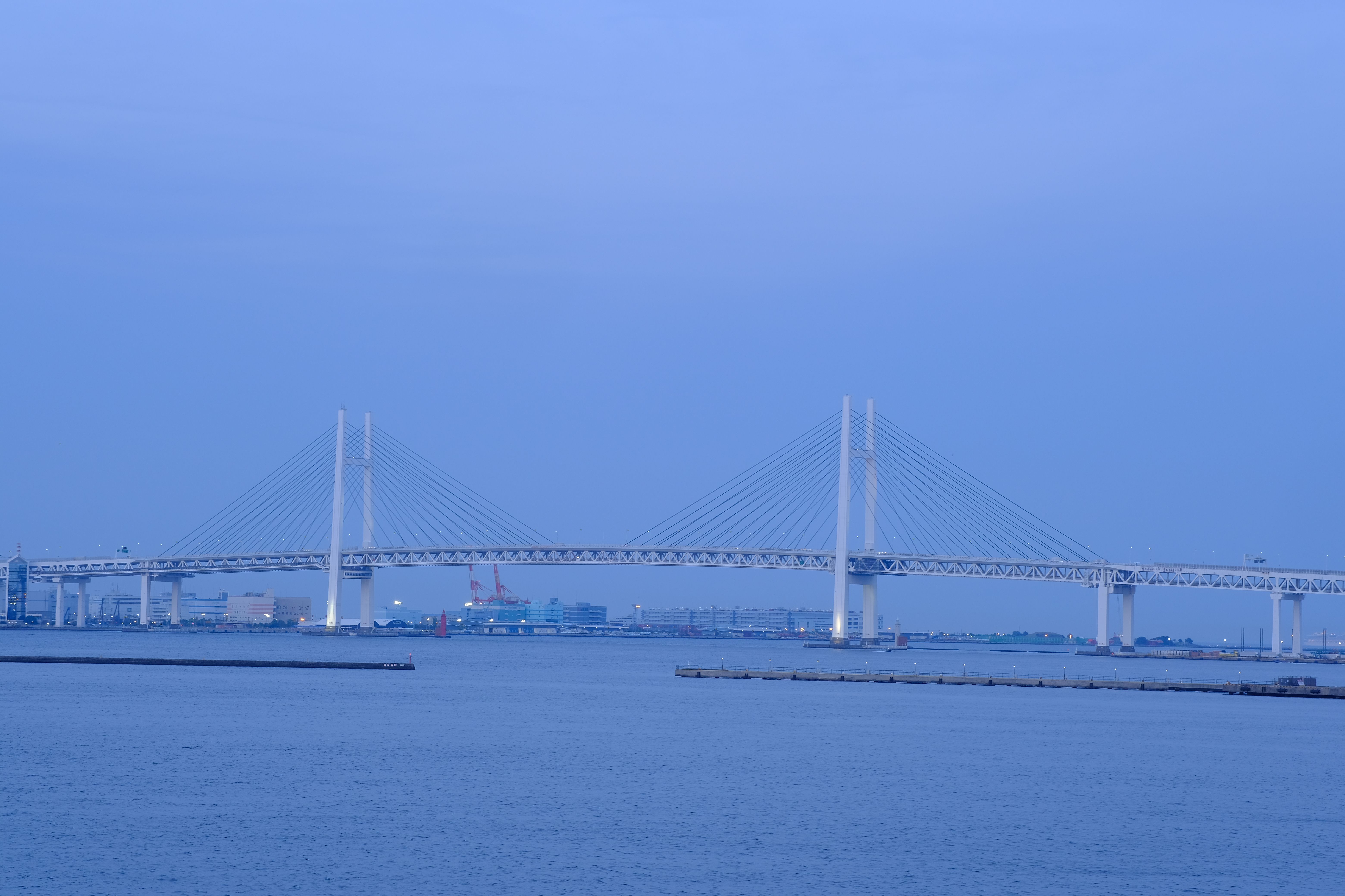 Tranquil view of the iconic Yokohama Bay Bridge spanning the harbor under a serene evening sky.