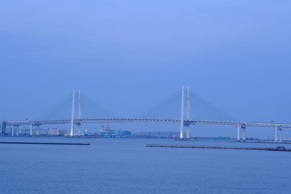 Tranquil view of the iconic Yokohama Bay Bridge spanning the harbor under a serene evening sky.