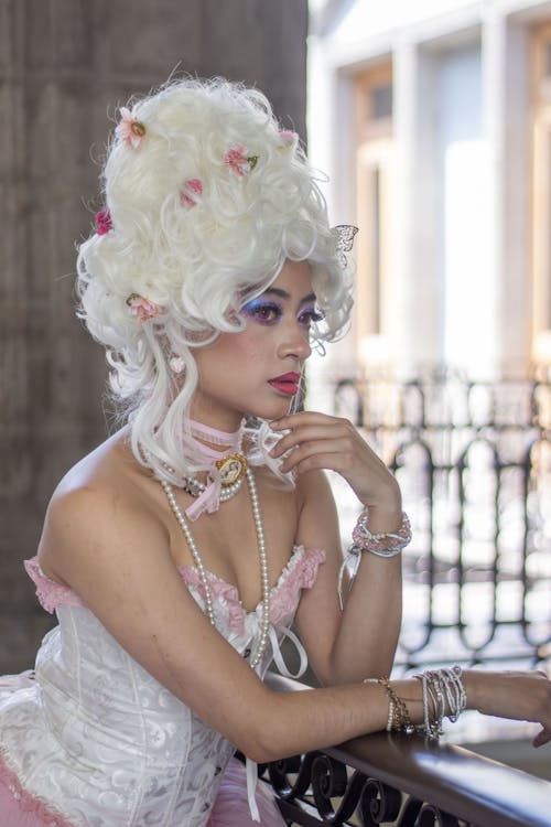 A woman with a white wig and pink dress