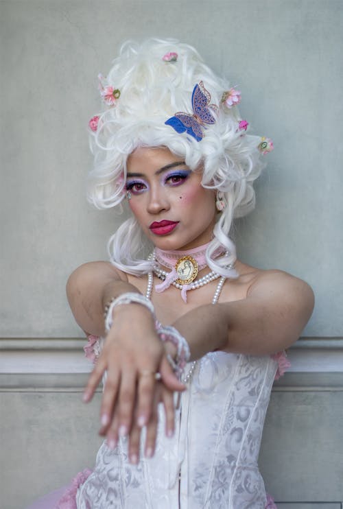 A woman with white hair and a pink dress