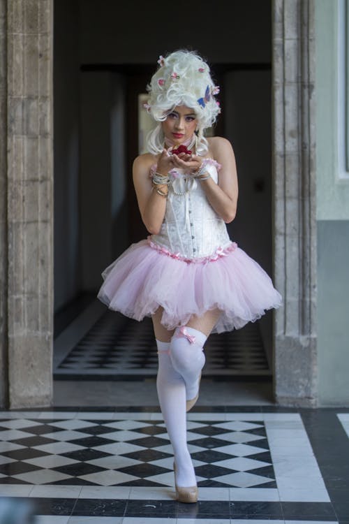 A woman in a tutu and white dress holding a cupcake