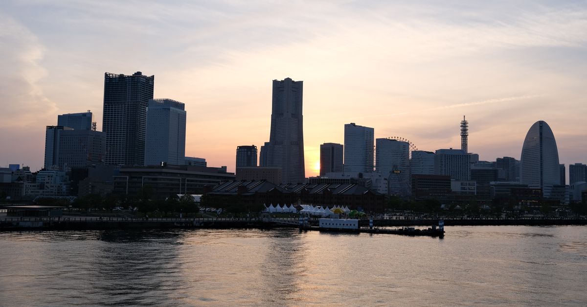 Stunning sunset view of Yokohama's skyline with reflections on the water, capturing modern architecture and urban beauty.