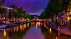 阿姆斯特丹运河的夜色充满活力，倒影与城市灯光丰富多彩