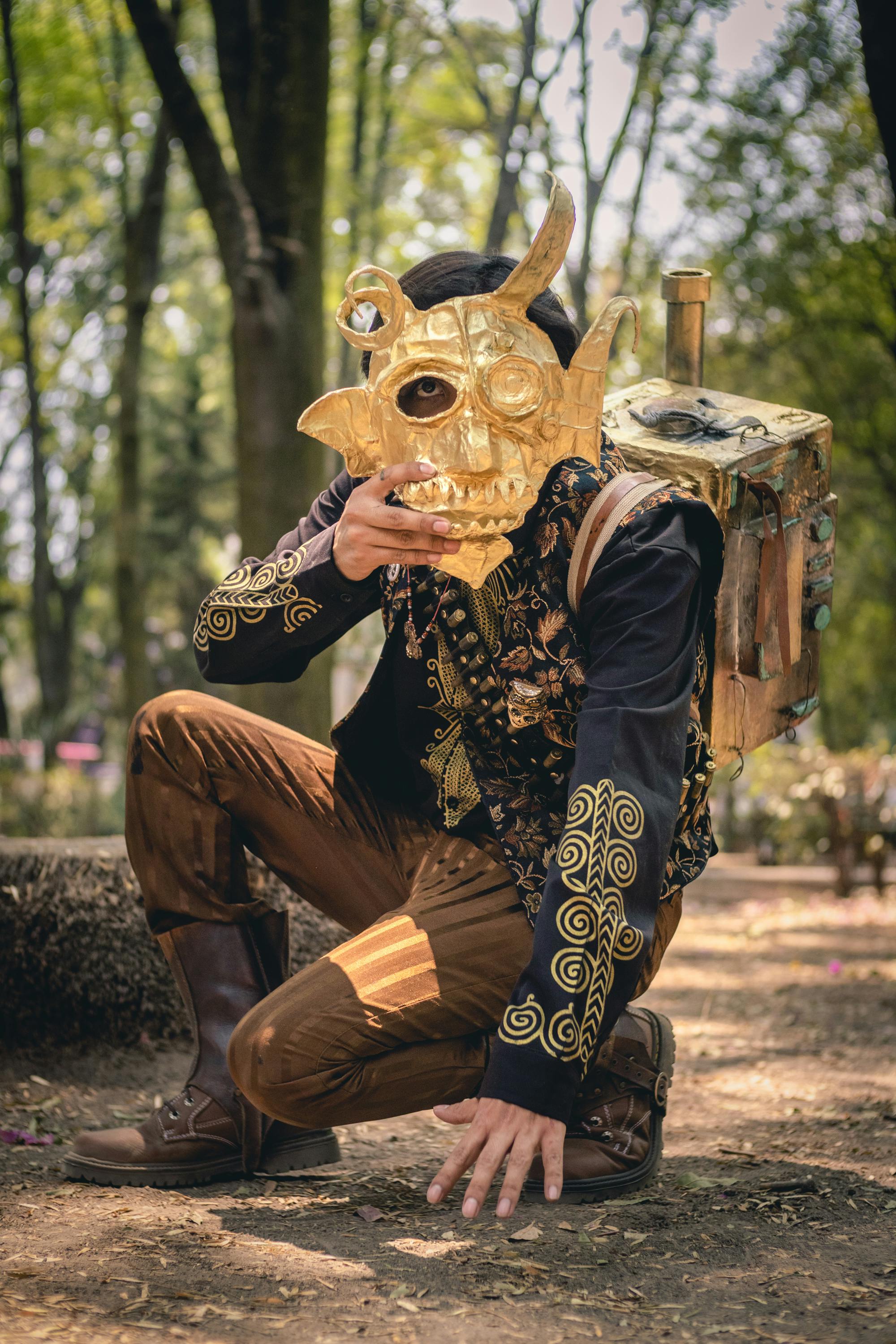 man crouching with golden mask