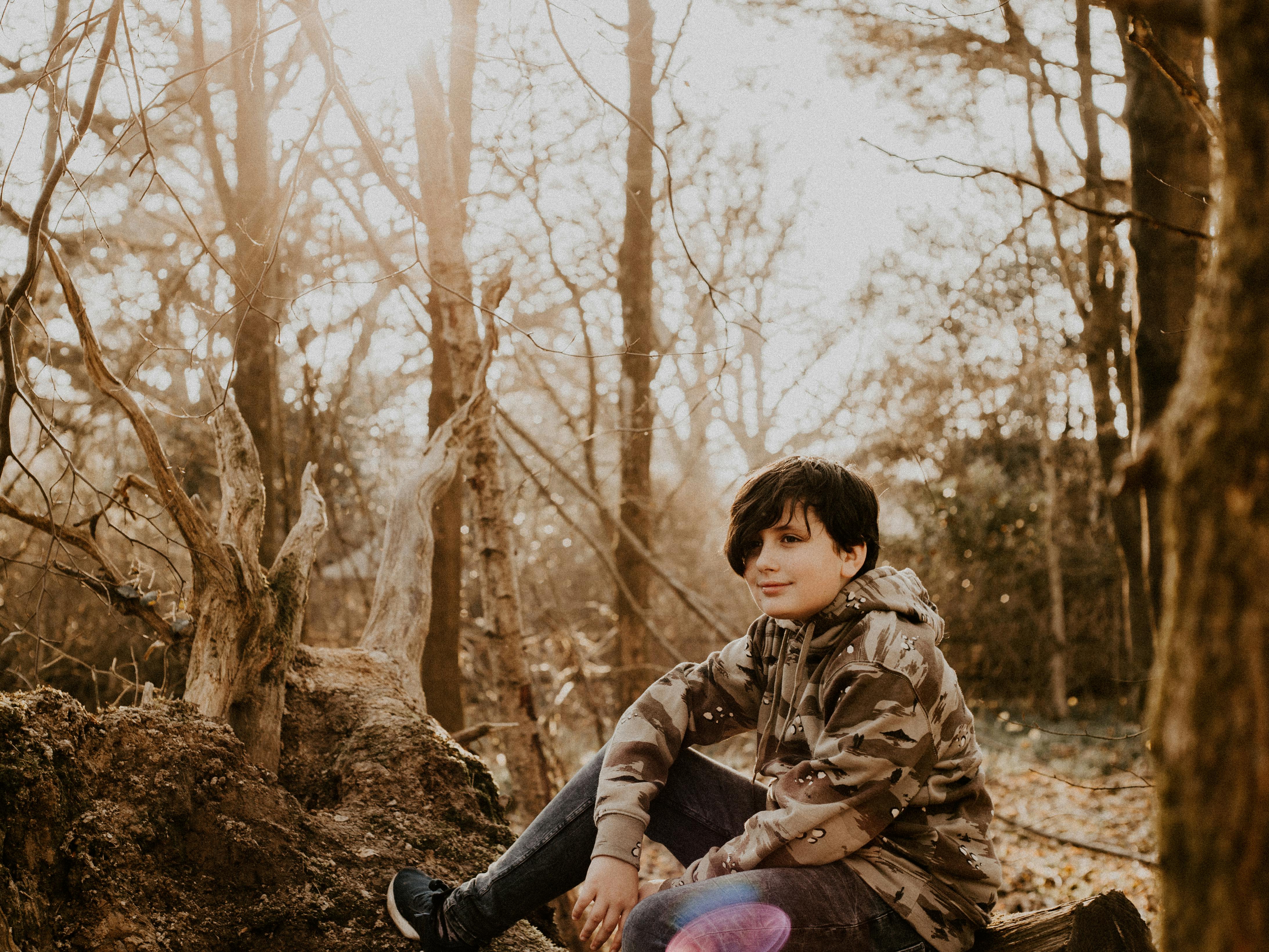 Boy in Brown and Black Camouflage Hoodie Sits on Tree