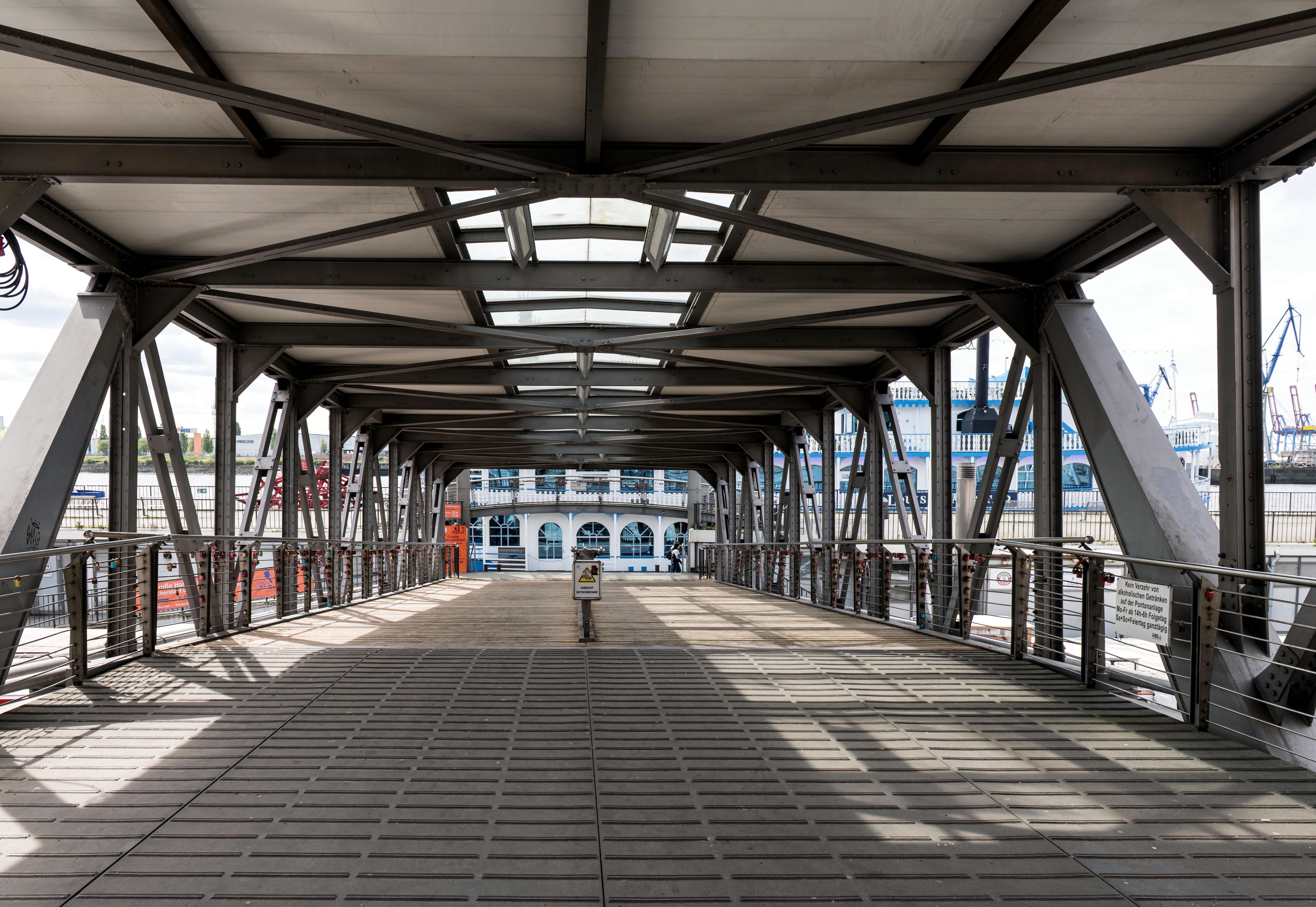 A modern footbridge in Hamburg provides a clear view of the bustling harbor area.