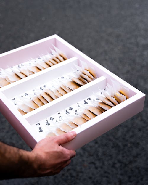 A person holding a tray with a box of cookies