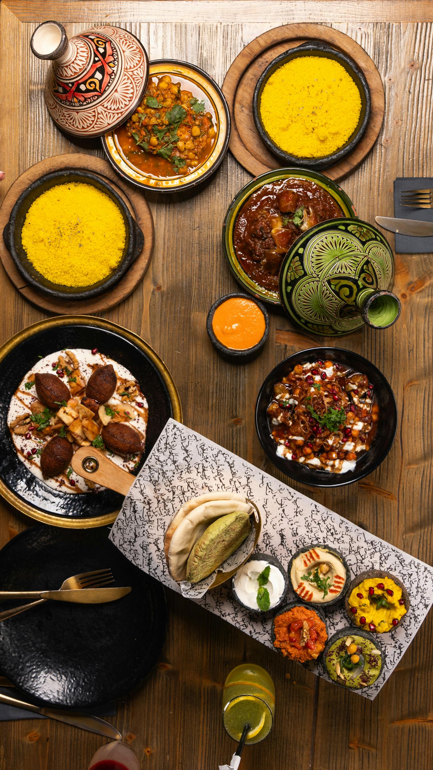 A vibrant spread of Middle Eastern cuisine with colorful dishes on a wooden table, viewed from above.