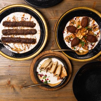 Top view of Middle Eastern dishes including kebabs and kibbeh served on a wooden table.