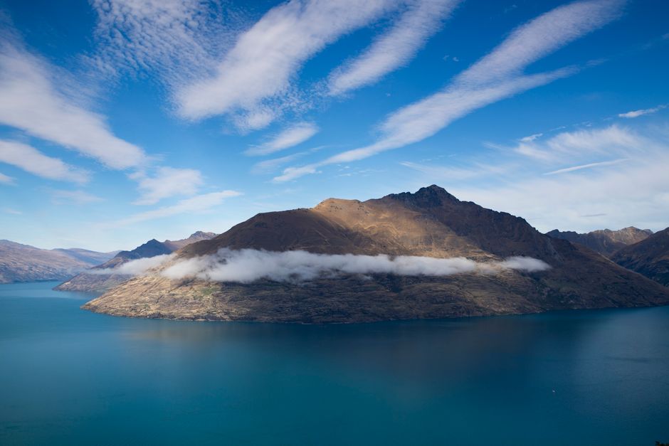 Amazing Milford Sound Heli Tour from Queenstown with 2 Alpine Landings Review Review 2026 - Stunning view of an island with mountains reflecting in the tranquil waters under a clear sky.