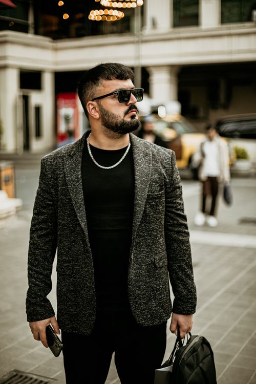 Free Portrait of a stylish man in urban fashion, wearing sunglasses and holding a bag in Baku, Azerbaijan. Stock Photo