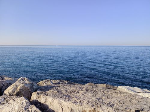 Free Peaceful view of the Adriatic Sea from the rocky coastline in Rimini, Italy. Clear blue skies above. Stock Photo