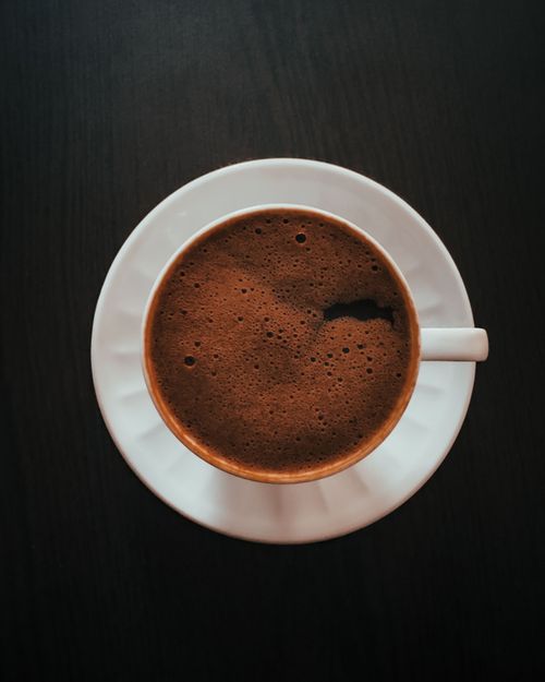 Free A top view of a foamy black coffee in a white porcelain cup against a dark background. Stock Photo