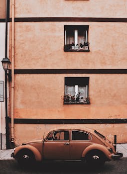 一辆经典的大众甲壳虫停在一条乡村街道上，背景是古老的建筑