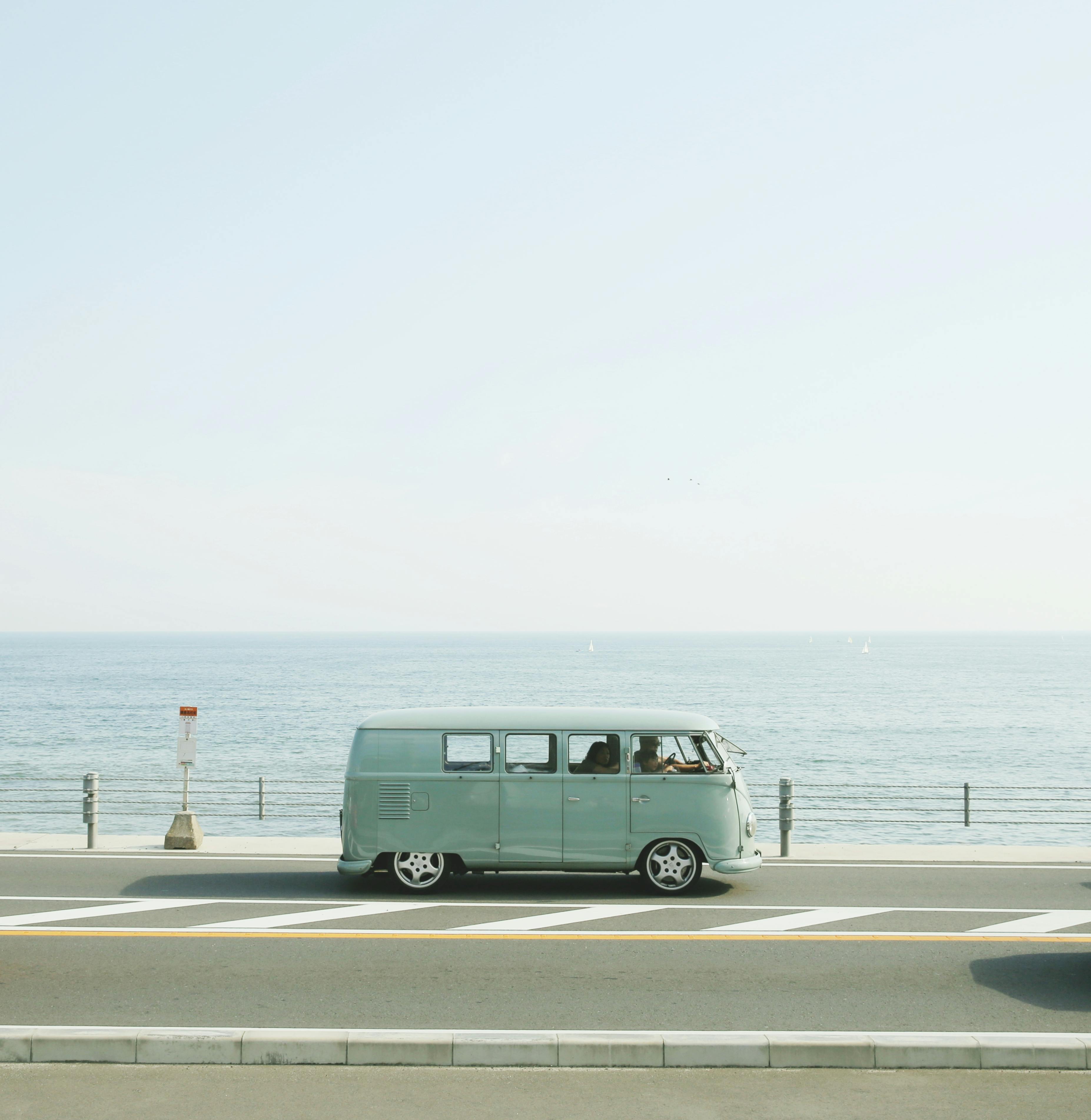 van parked beside the road near handrail and ocean