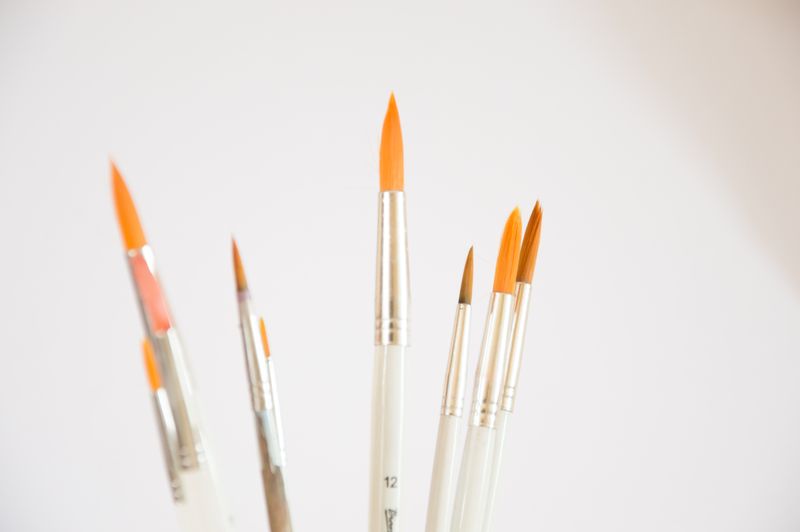 Fine pointed brushes against a plain pale background