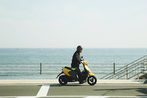 Man Riding Yellow Motor Scooter on Road