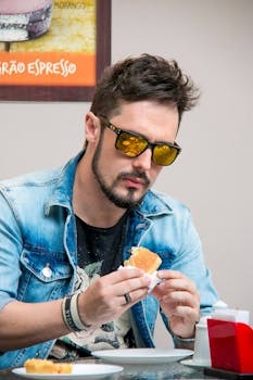 一位留着胡子、戴着墨镜的男子正在咖啡馆里用餐，悠闲地享受室内时光