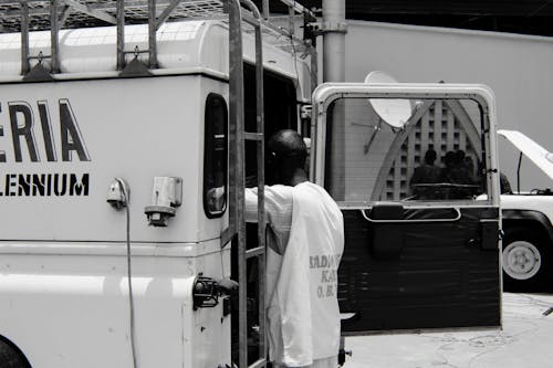 Grayscale Photography of Man Standing Behind Utility Truck